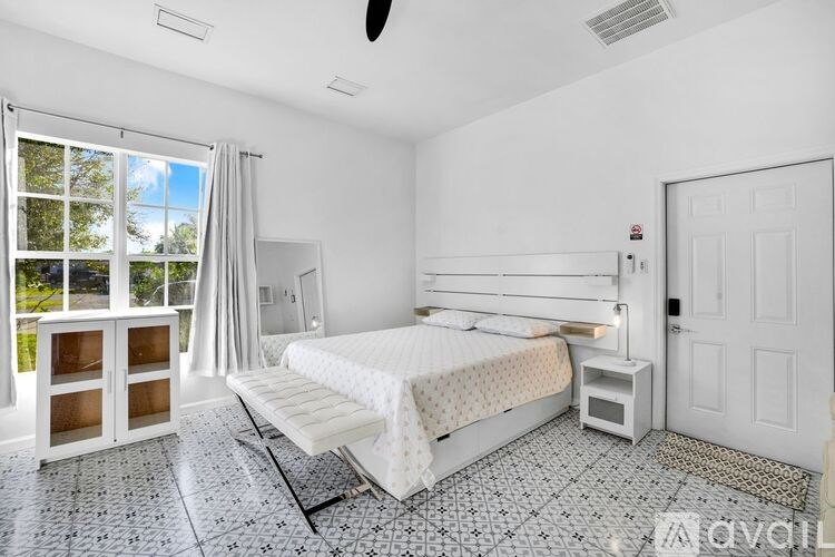 A bedroom with a large bed, a window with curtains, and a ceiling fan.
