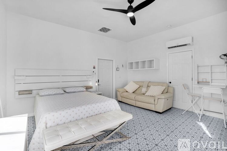 A bedroom with a bed, couch, and chair.