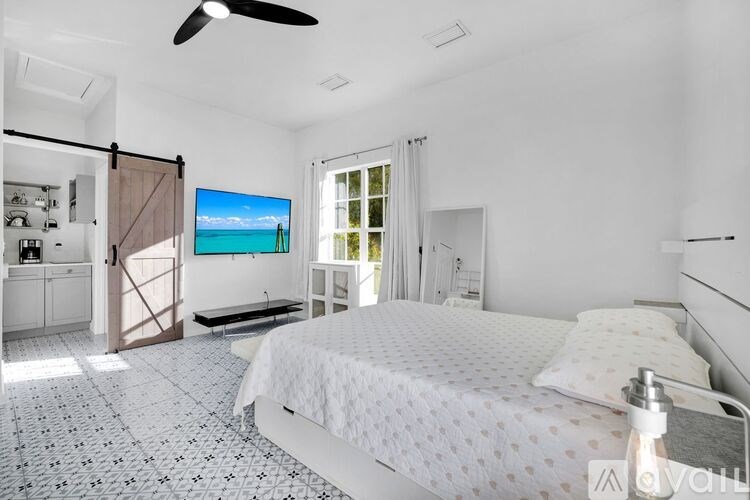 A bedroom with a bed, a ceiling fan, and a painting on the wall.
