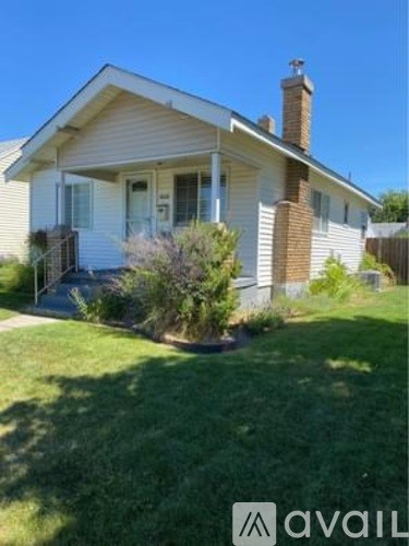 A house with a white siding and a brown roof with a chimney.