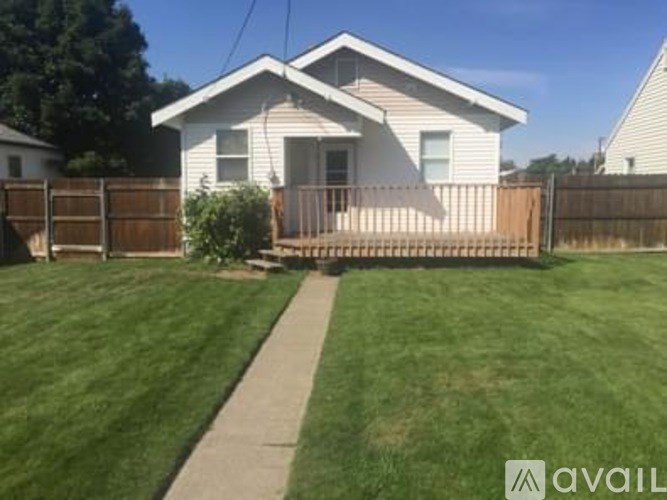 A house with a white siding and a brown fence is for sale.