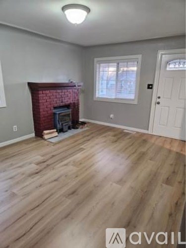 A room with a fireplace and wood flooring.