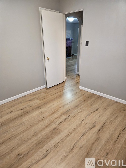 A room with a white door and wooden flooring.