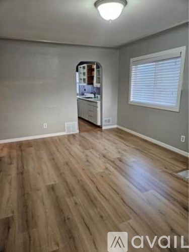 A room with wooden flooring and a window with blinds.