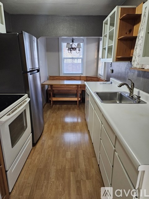 A kitchen with a black refrigerator and wooden floors.