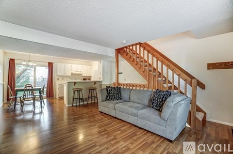 A living room with a grey couch and a wooden staircase.
