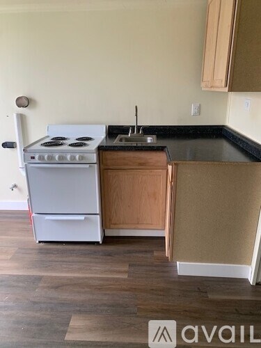 A kitchen with a white stove and wooden cabinets.
