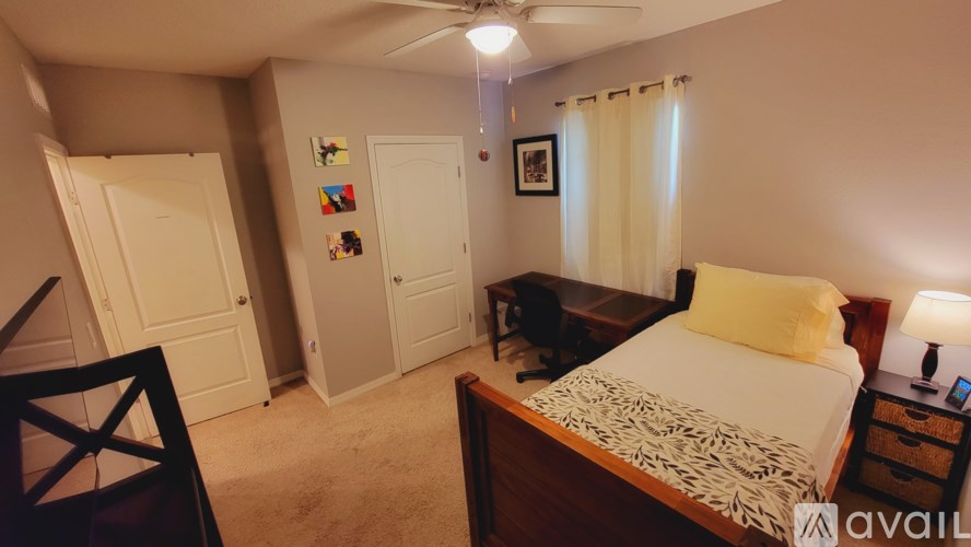 A bedroom with a bed, a chair, a table, and a ceiling fan.