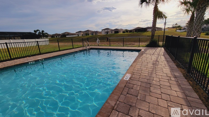 A swimming pool surrounded by a black fence and brick walkway.