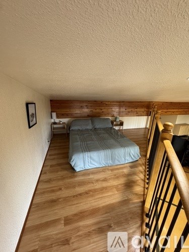 A bedroom with a bed and a wooden staircase.