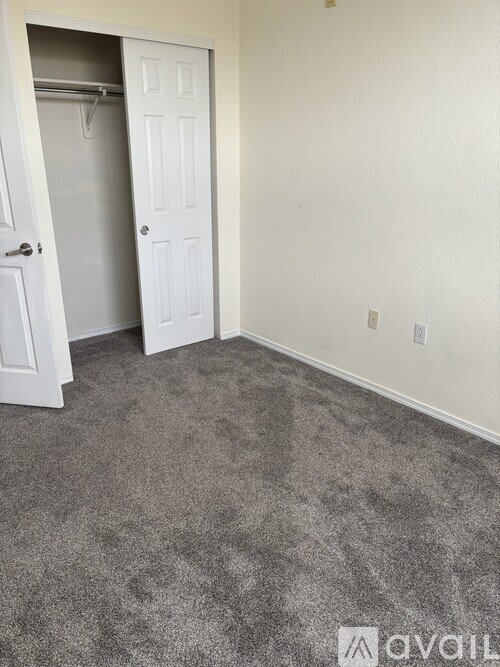 A room with a carpeted floor and a door with a white frame.