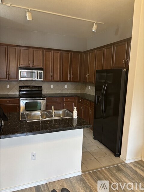 A kitchen with wooden cabinets and a black fridge.
