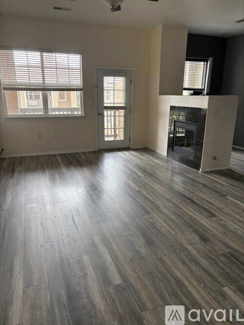 A spacious room with wood flooring and a fireplace.