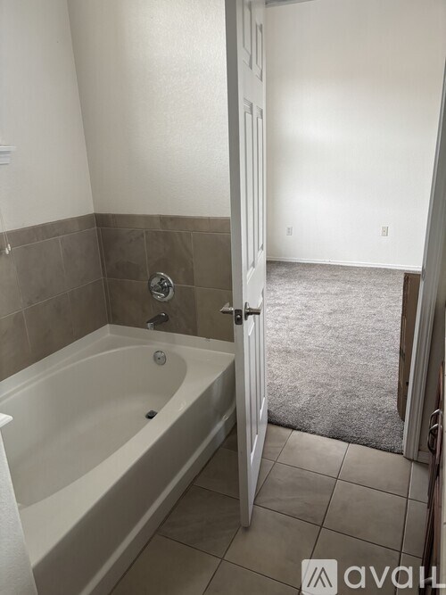 A bathroom with a tub and a doorway leading to a hallway.