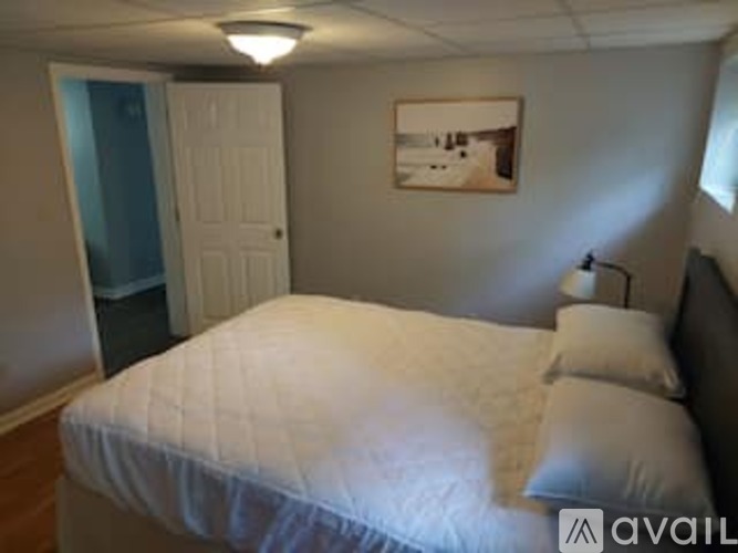 A bedroom with a bed, pillow, and a picture on the wall.