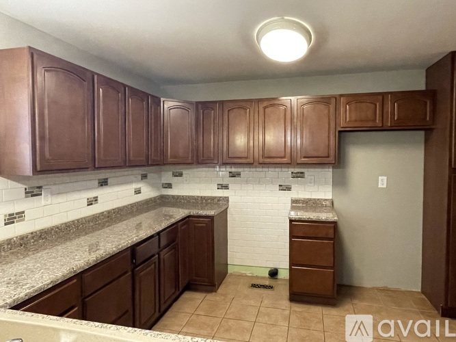 A kitchen with brown cabinets and a granite countertop.