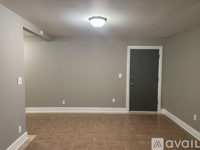 A room with a black door and a brown tile floor.