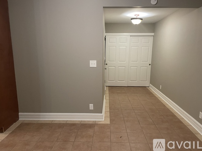 A room with a white door and brown tile flooring.