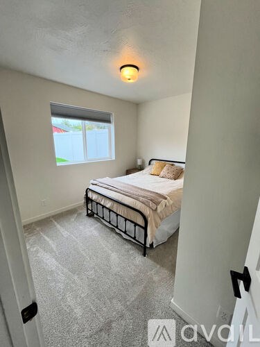 A bedroom with a bed, window, and carpeted floor.