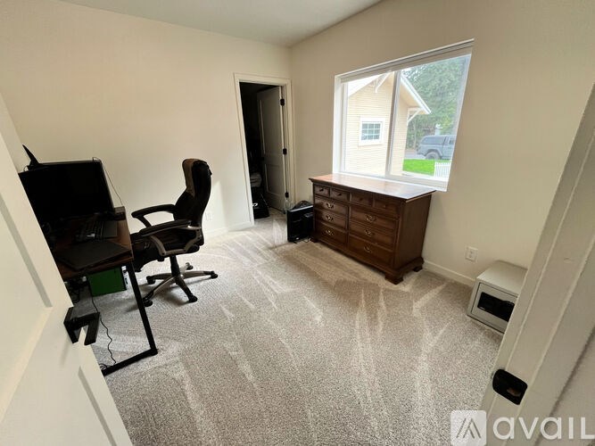 A room with a carpeted floor, a chair, a television, and a window.