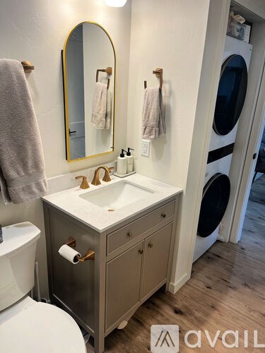 A bathroom with a white sink and a round mirror.