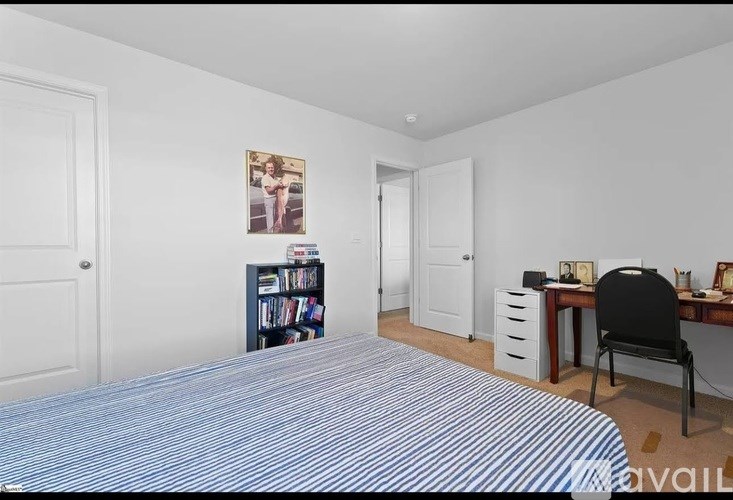 A bedroom with a bed, desk, and chair.