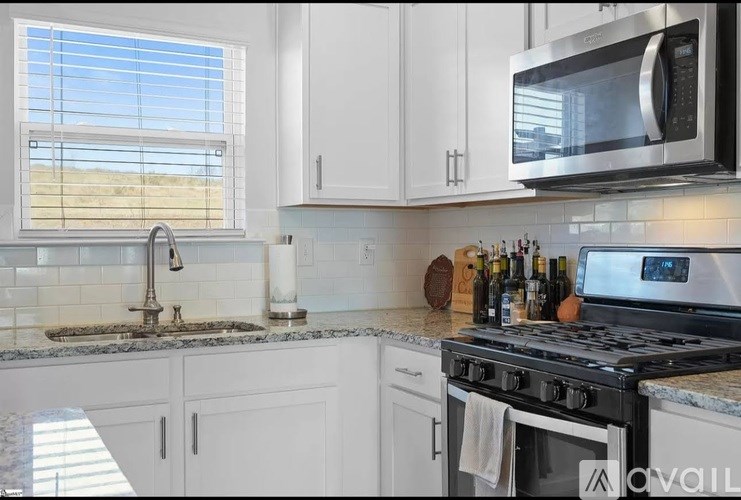 A kitchen with a stove, sink, and cabinets.