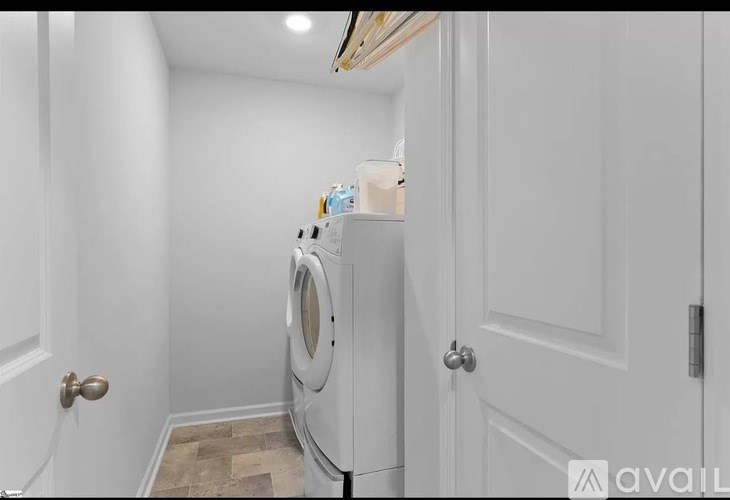 A white washing machine is in a small laundry room.