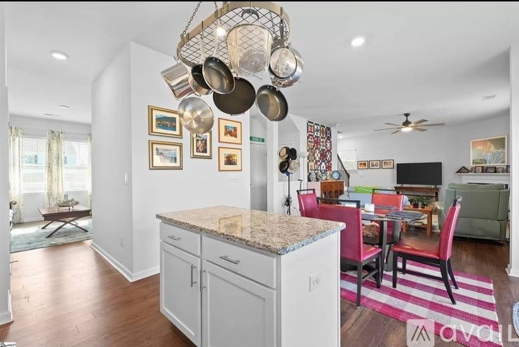 A kitchen with a granite countertop and a dining area with a red table and chairs.