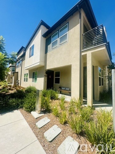 A modern house with a front yard and a clear blue sky.
