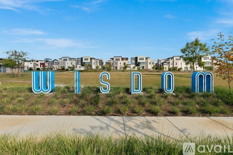 Wisdom spelled out in large blue letters in front of a residential area.