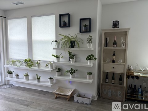 A spacious living room with a grey sofa and a kitchen in the background.