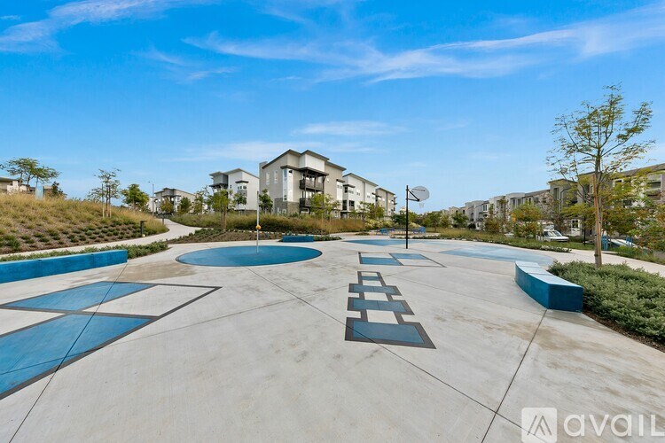 A playground with a basketball hoop and a blue and white striped pattern on the ground.