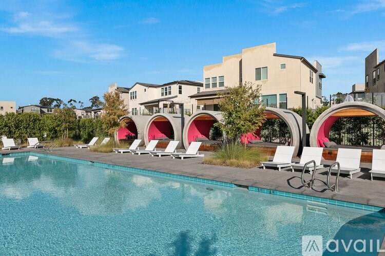 A pool with chairs and a building in the background.