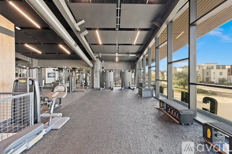 A gym with a variety of equipment including treadmills, weights, and exercise machines.