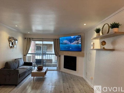 A living room with a couch, a coffee table, and a television displaying a snowy landscape.