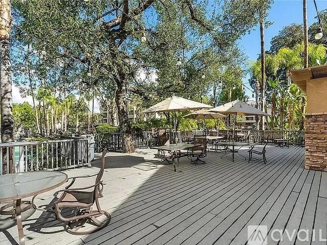 A wooden deck with chairs and umbrellas surrounded by trees.