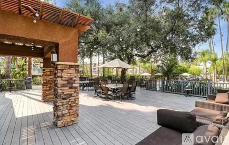 A wooden deck with a stone pillar and a gazebo in the background.