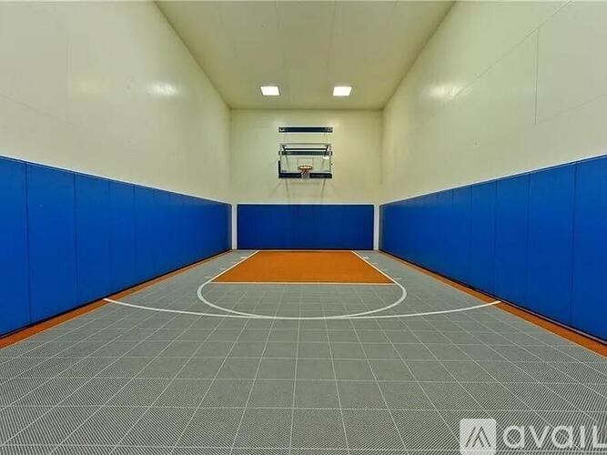 A basketball court with a hoop and orange mat.
