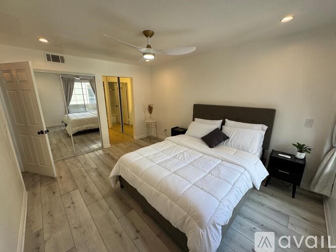 A bedroom with a large bed and a ceiling fan.