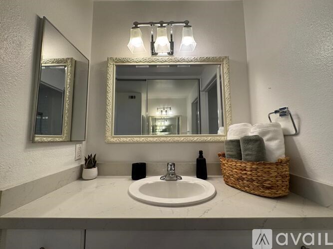 A bathroom with a sink, mirror, and lighting fixture.