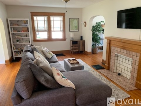 A living room with a grey couch and a fireplace.