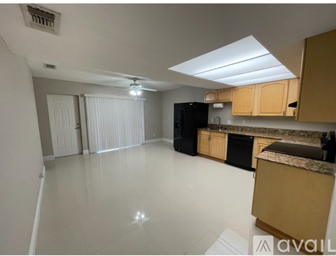 A kitchen with a black fridge and wooden cabinets.