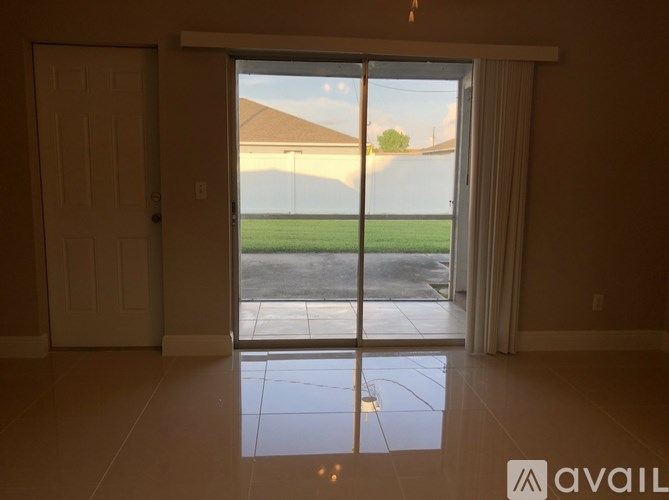 A room with a sliding glass door leading to a green lawn.