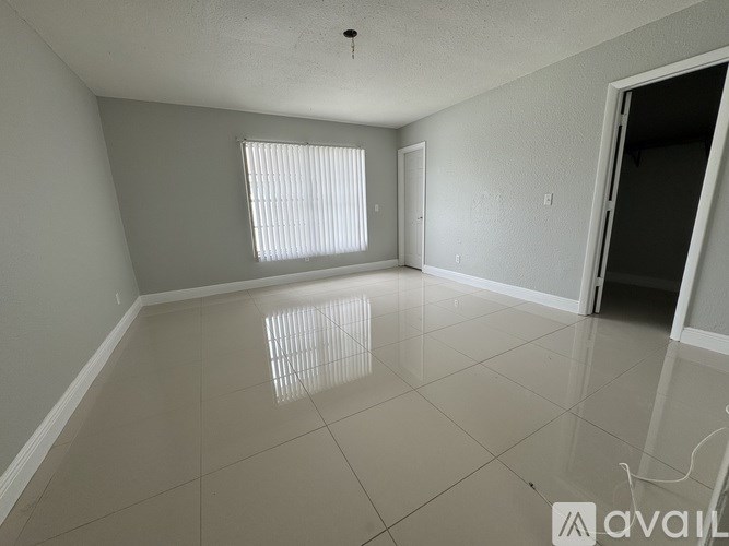 A spacious room with a tiled floor and a window with blinds.