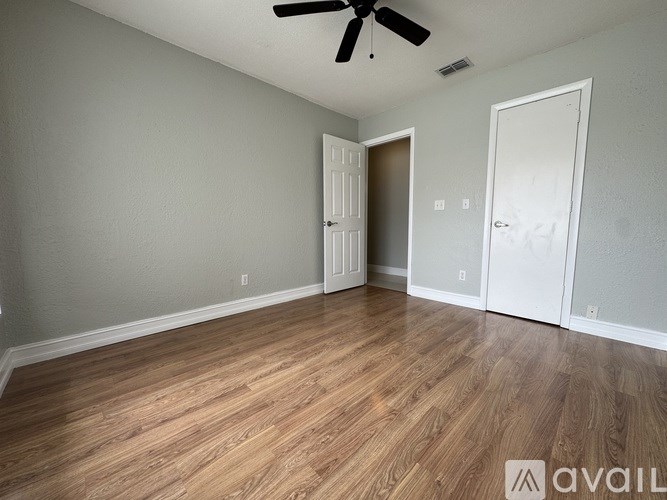A room with a ceiling fan and wooden flooring.