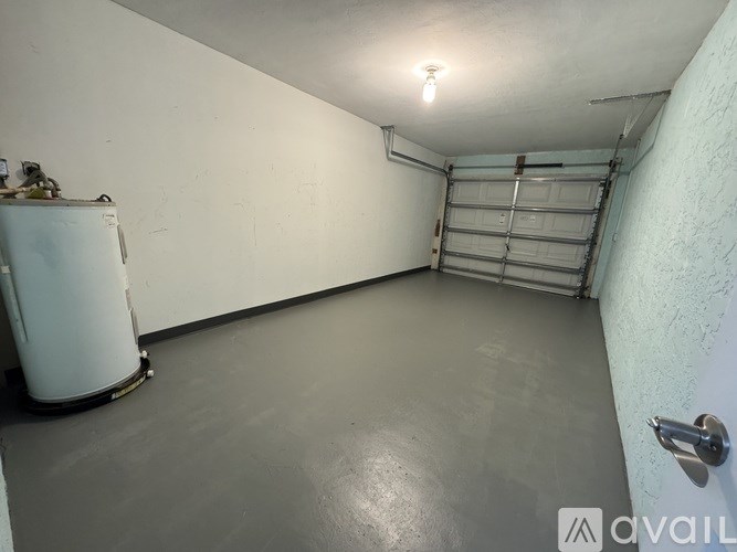 A white wall with a garage door opener and a white refrigerator in a room.