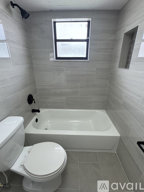 A white toilet sits next to a white bathtub in a bathroom.