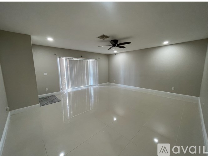 A spacious room with a ceiling fan and a window with blinds.