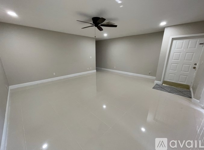 A spacious room with a ceiling fan and a door.